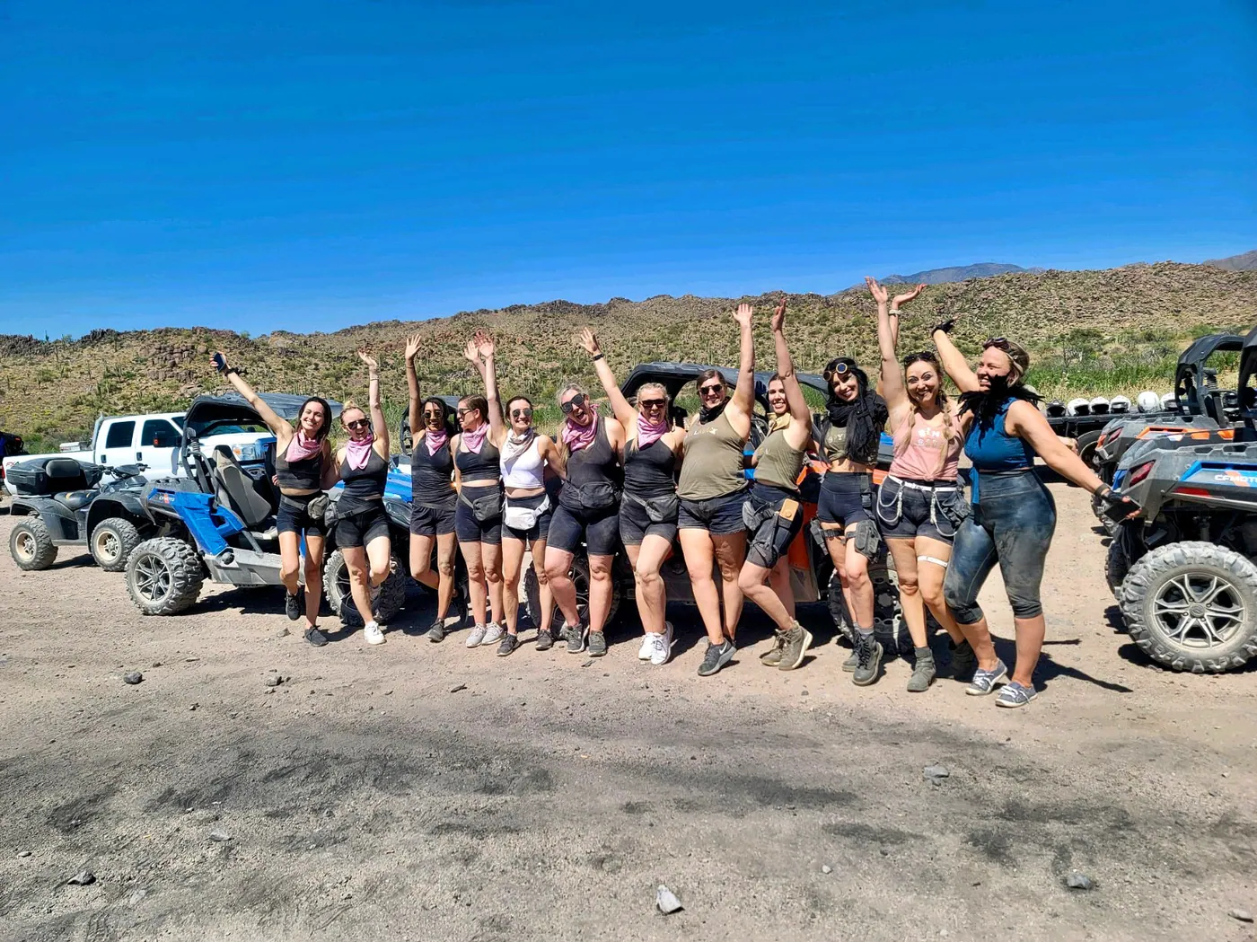 A bachelorette group cheering in front of a lineup of sand buggies near Scottsdale