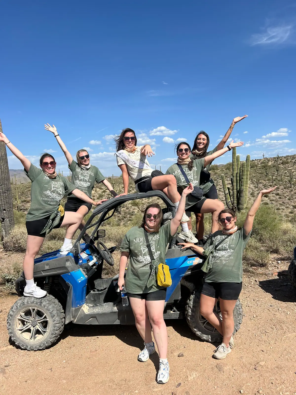 A bachelorette group in green celebrating on a blue sand buggy