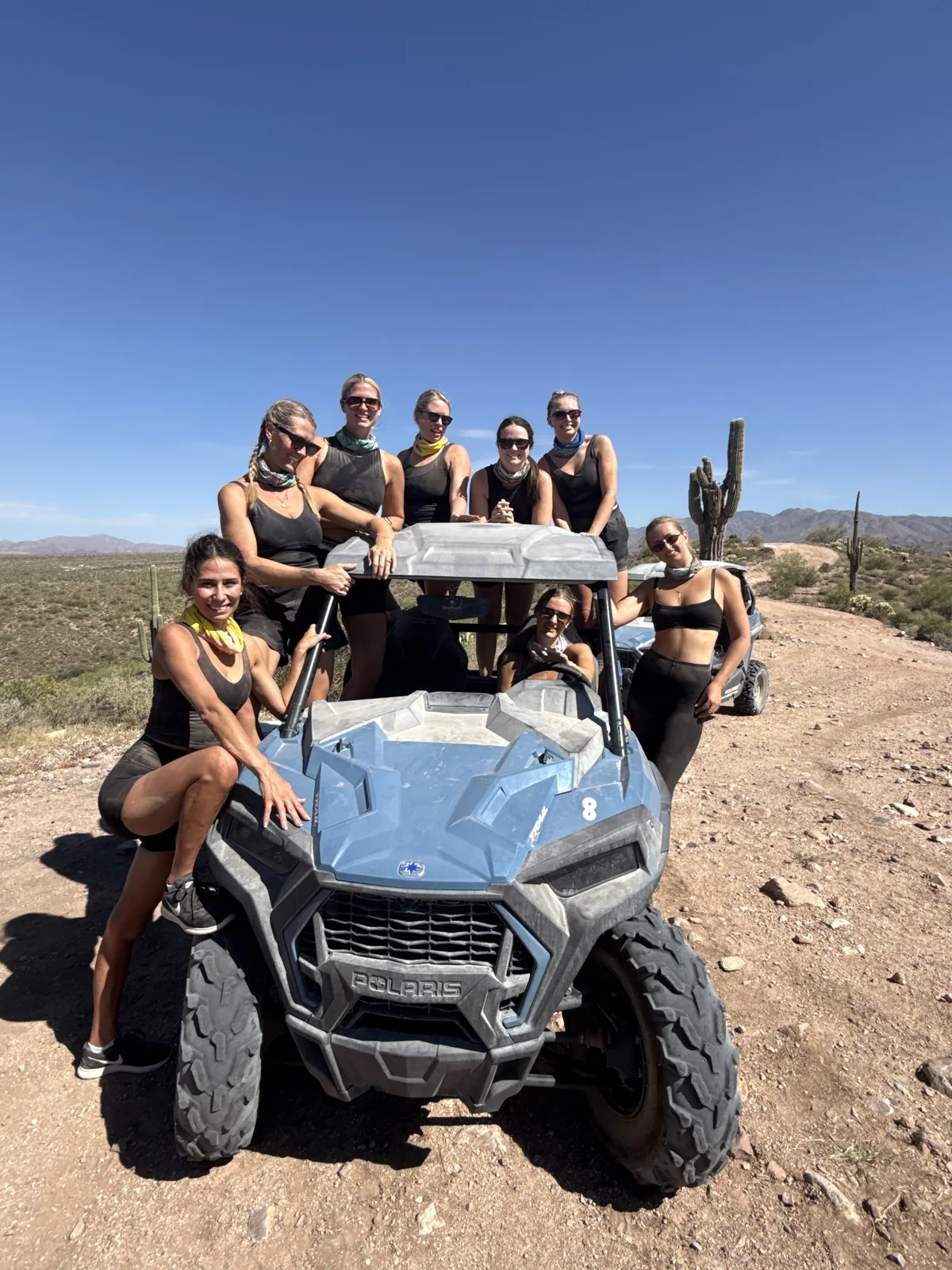 A women's bachelorette group gathered on their Polaris RZR in the desert near Scottsdale