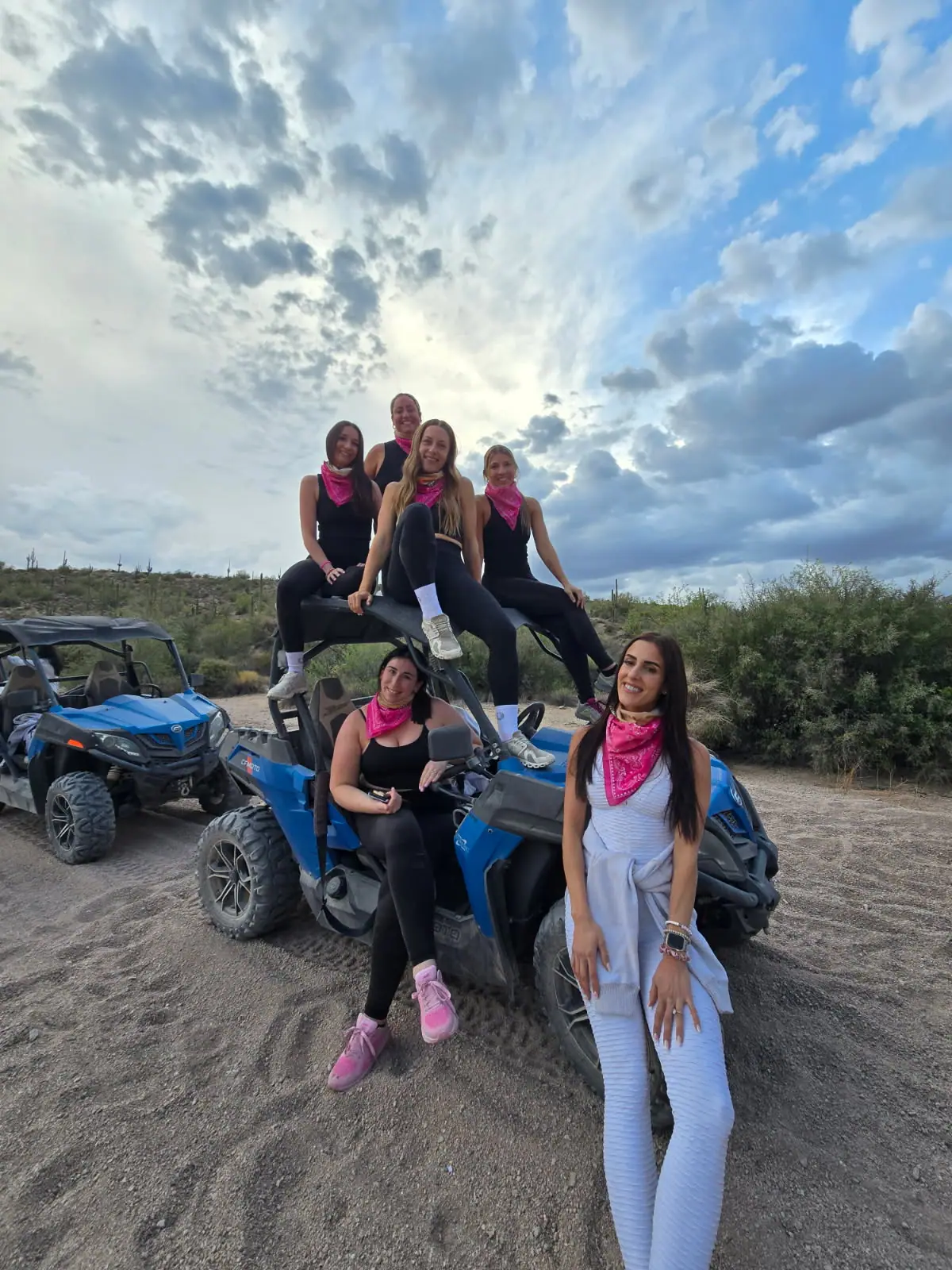 A bachelorette group in pink on a blue buggy at dusk