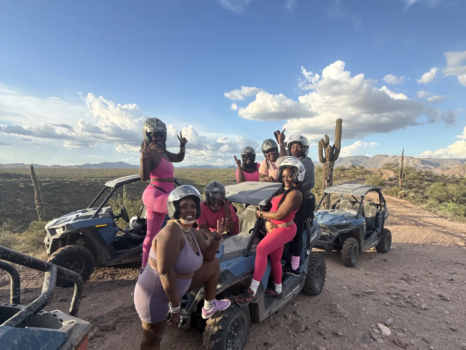 A bachelorette party in pink gathered by their UTVs under a dramatic desert sky near Scottsdale