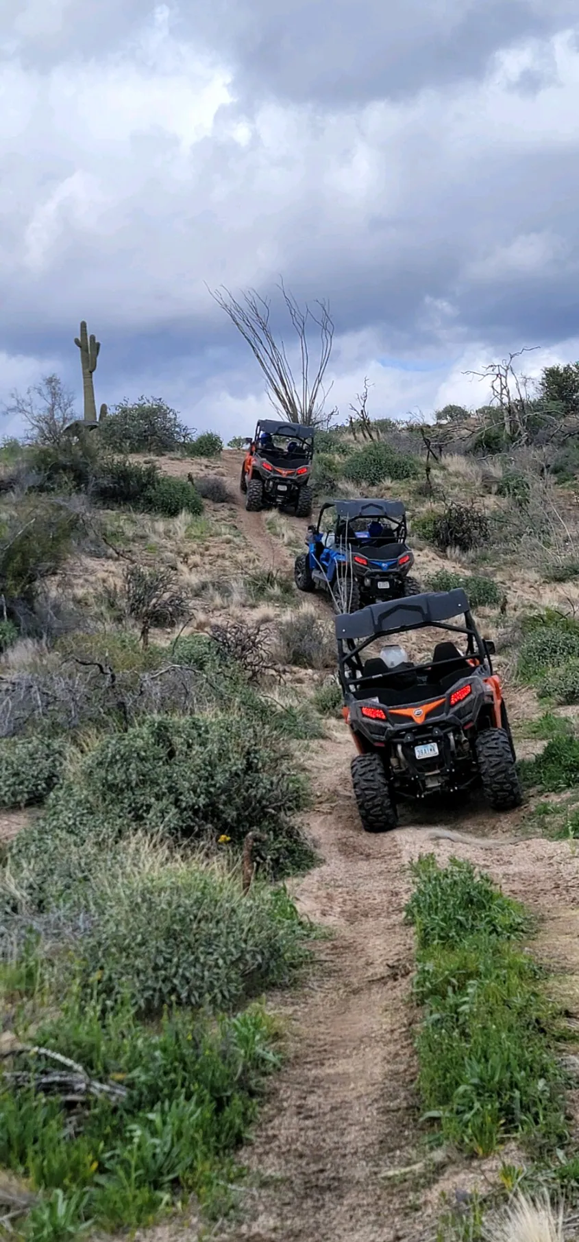 A private VIP convoy climbing a rugged Sonoran Desert trail under a dramatic storm sky near Scottsdale