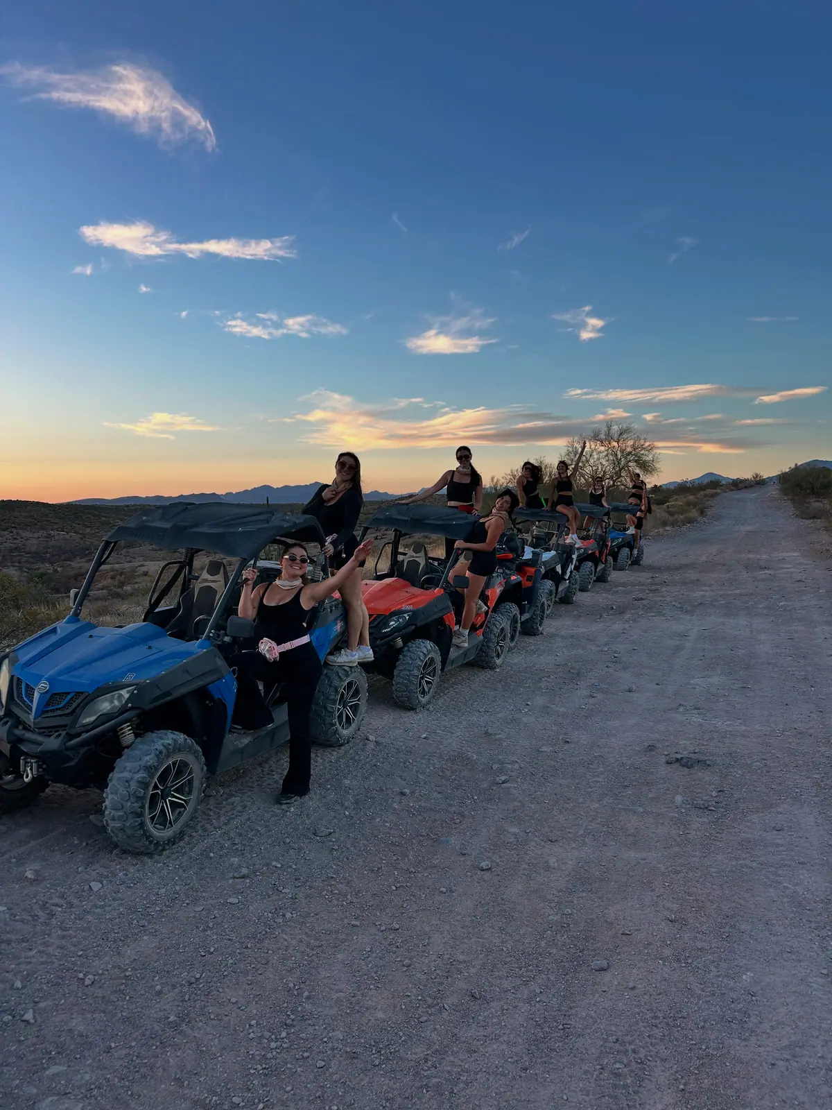 A lineup of sand buggies and riders at dusk in the Sonoran Desert