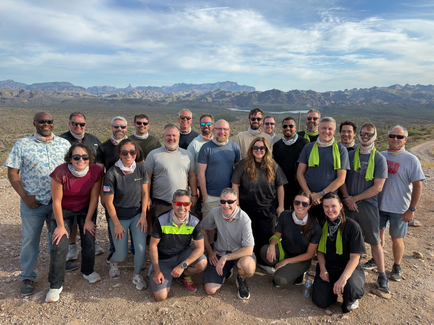 A corporate team in neck gaiters poses on a desert ridge in the Tonto National Forest during a guided UTV tour near Scottsdale