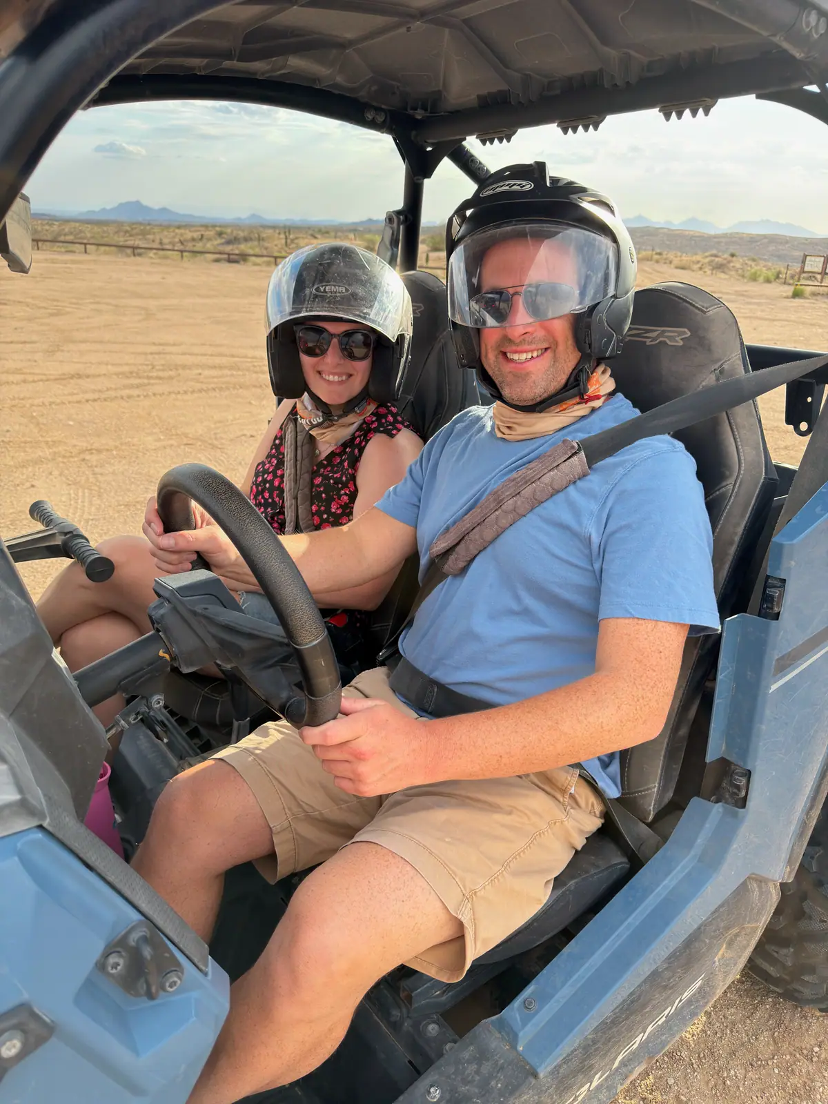 A couple wearing helmets seated in a Polaris RZR ready for a Scottsdale desert tour