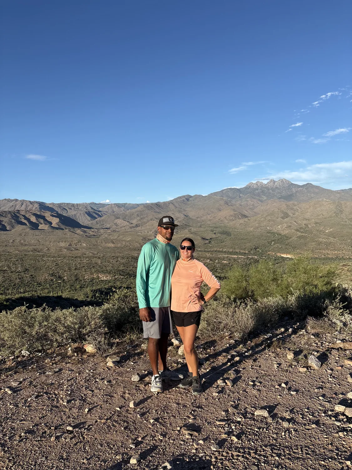 A couple on a ridge overlook with the Four Peaks behind them on a Scottsdale desert UTV tour
