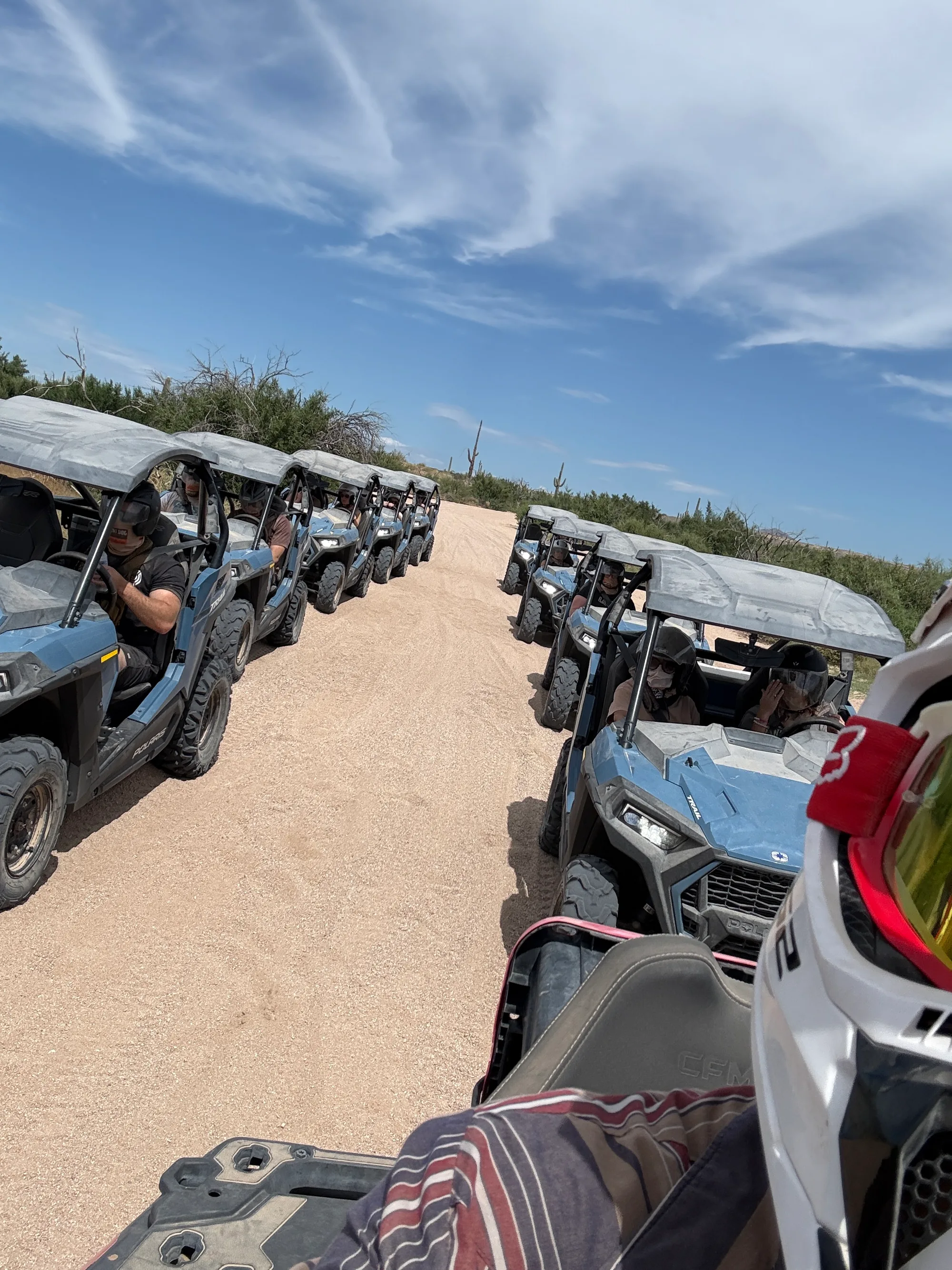 Driver view of a Polaris RZR convoy lined up on a sandy trail near Scottsdale
