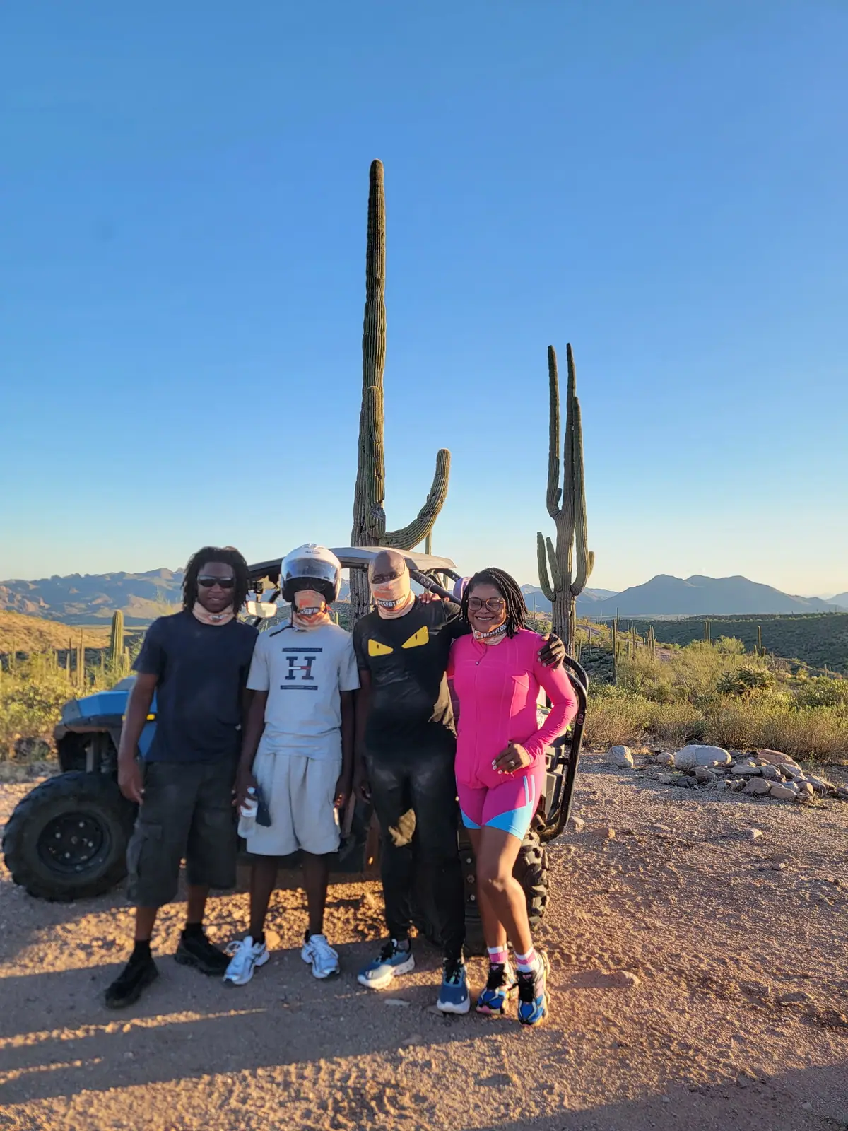 A group of friends in front of a Polaris RZR and saguaros at sunset near Scottsdale