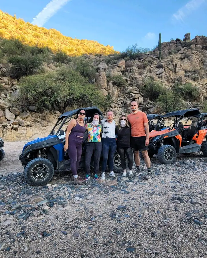 A group by a blue sand buggy on a golden-lit Scottsdale hillside