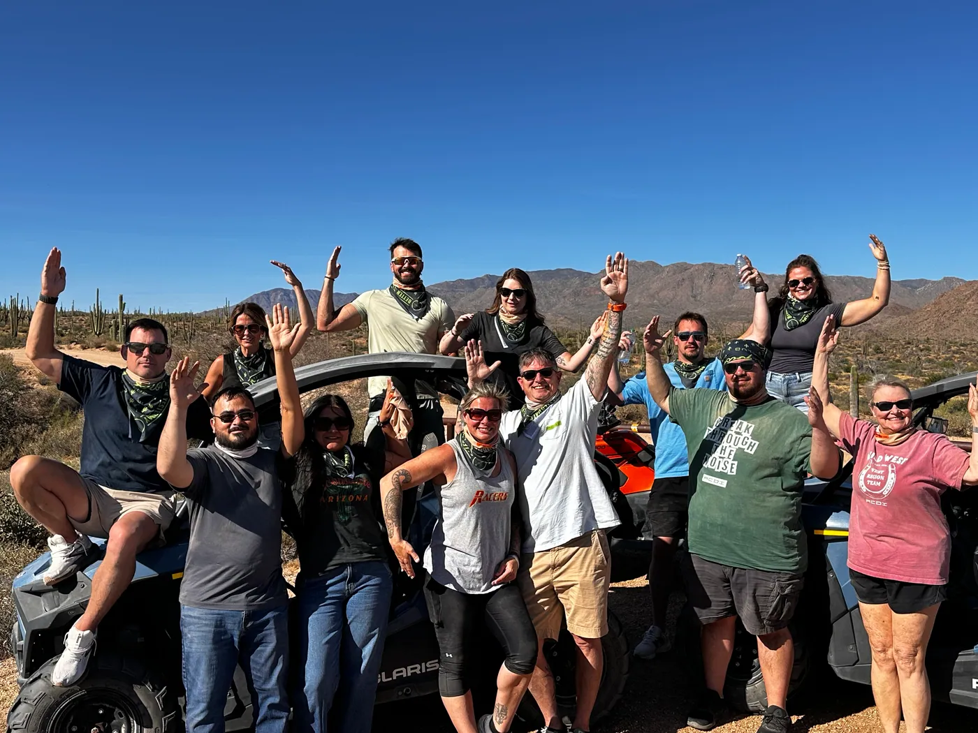 A group celebrating around their buggies with mountains behind on a Sonoran Desert tour