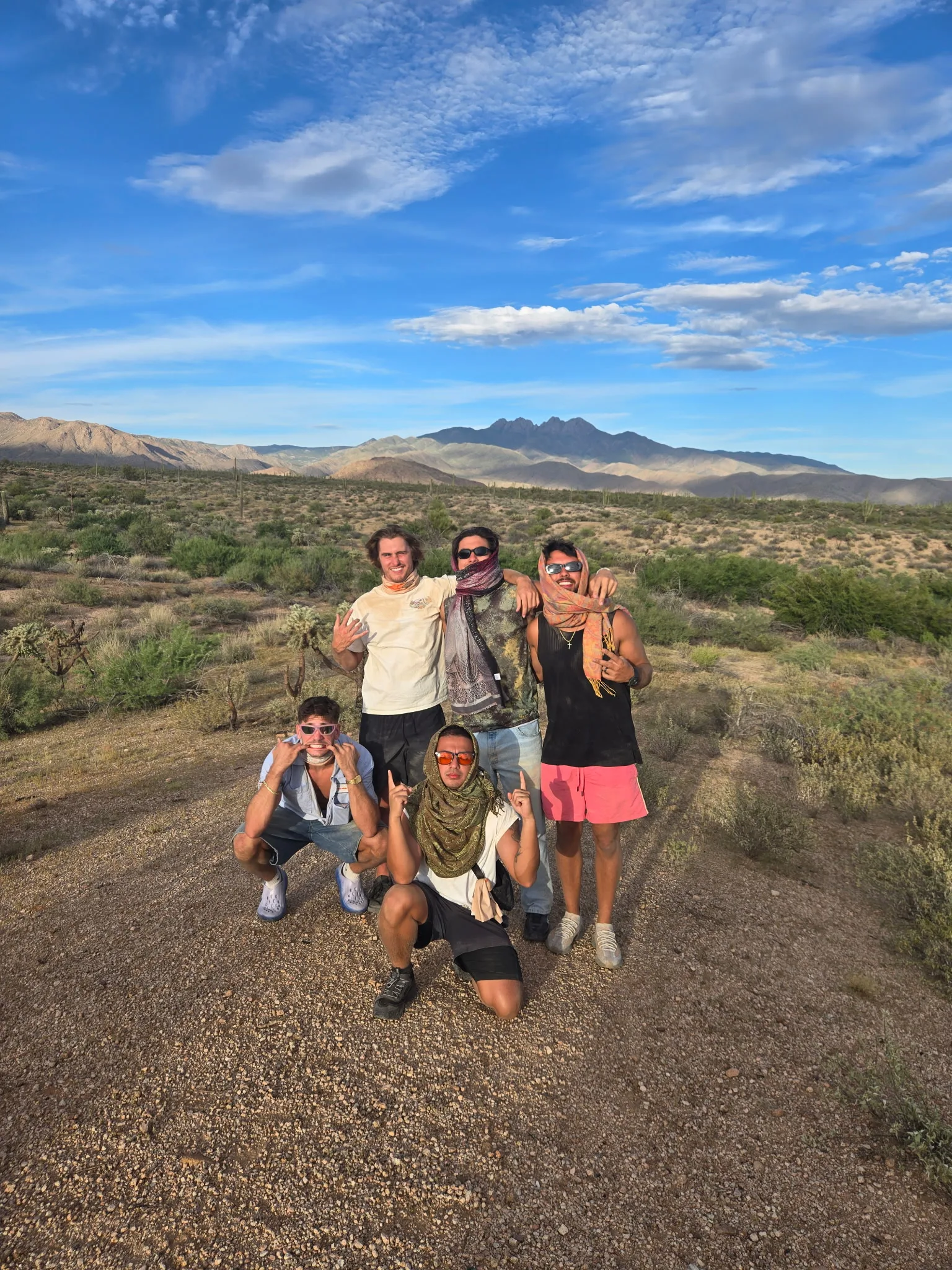 Five friends in bandanas posing in front of the Four Peaks on a guys trip UTV tour near Scottsdale