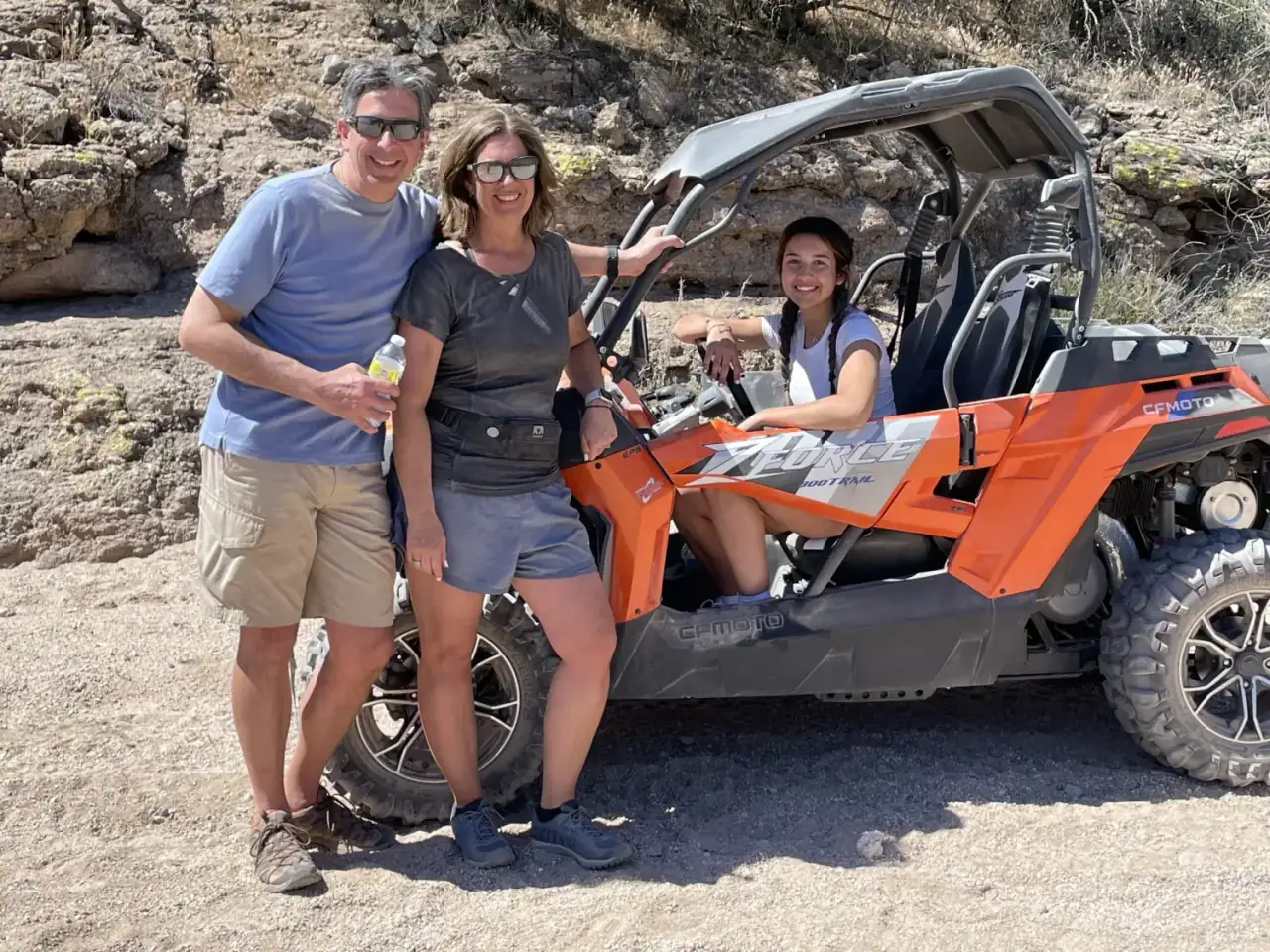 Happy family posing with an orange ATV in the desert