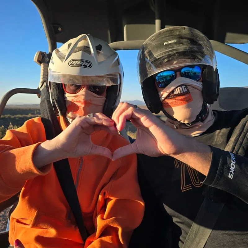 Couple making a heart shape with their hands during an ATV adventure