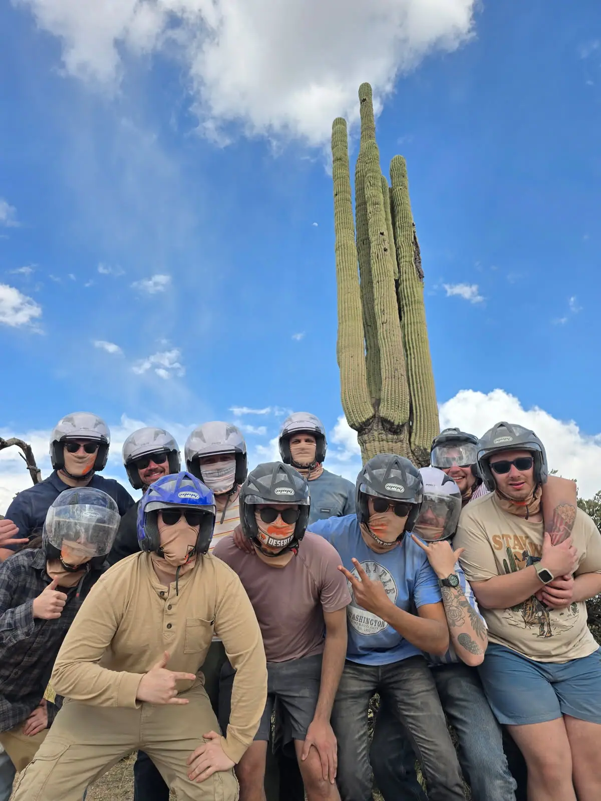 A group posing by a tall saguaro on a Scottsdale desert tour