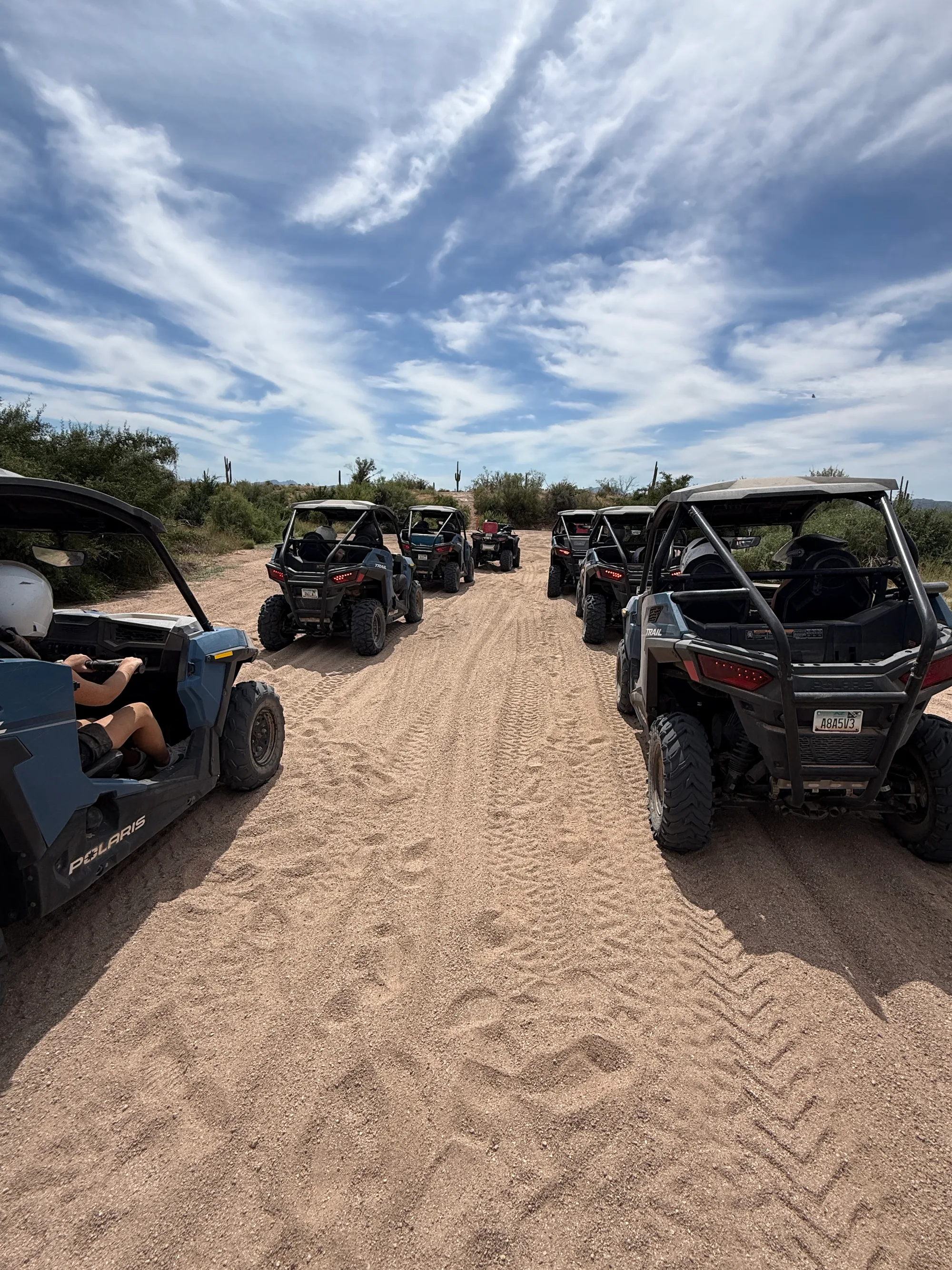 A fleet of Polaris RZR sand buggies rolling through deep sand on a Sonoran Desert trail near Scottsdale