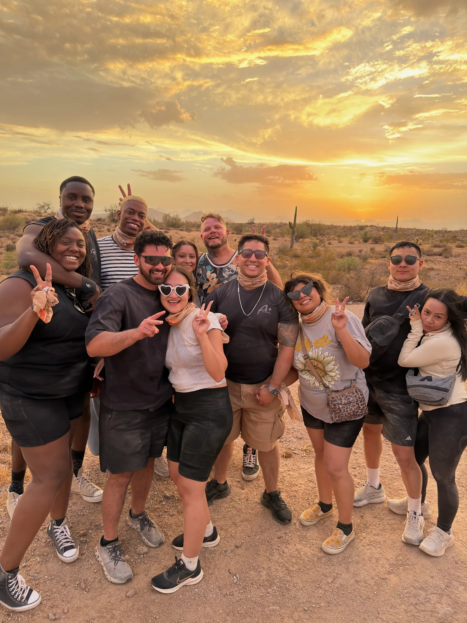 A smiling tour group throwing peace signs at sunset in the Scottsdale desert