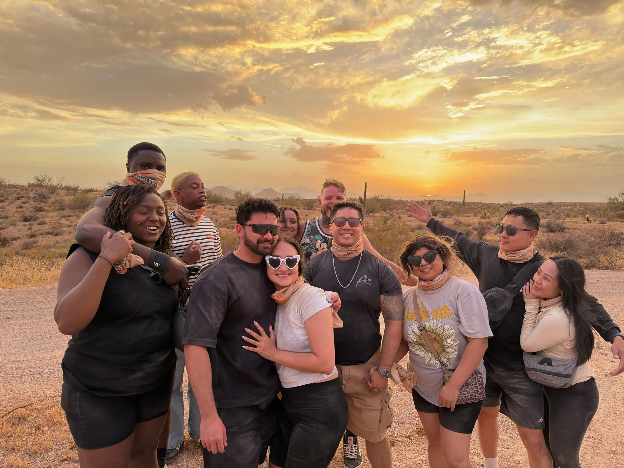 A Desert Dog tour group posing at sunset in their bandanas on a Scottsdale UTV tour