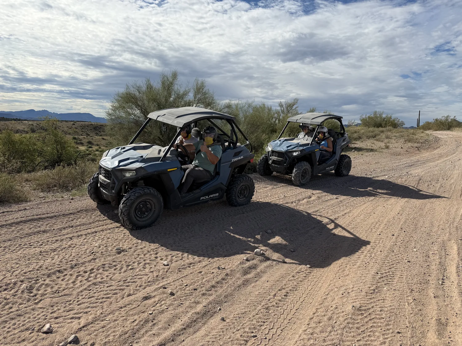 Two Polaris RZR buggies with riders aboard on a sandy Sonoran Desert trail near Scottsdale