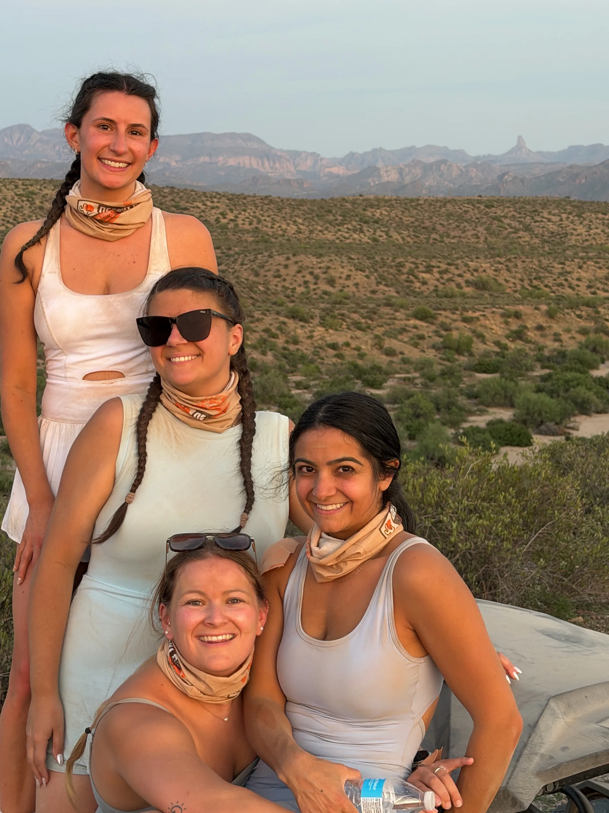 Four smiling women in Desert Dog gaiters at dusk in the desert on a Scottsdale UTV tour